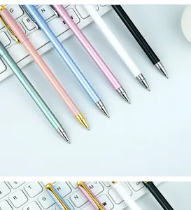 Close-up detail of stylish multi-colored metal gel pens placed on a white keyboard