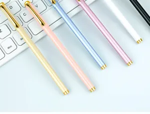 Detailed view of elegant colorful metal gel pens with gold trim placed on a keyboard