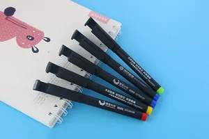 Detailed view of black gel pens with colorful mobile phone holder clips on a blue background
