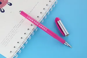 Close-up of pink customizable gel pen with advertising text on white spiral notebook