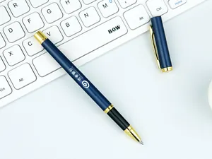 Detailed view of a navy blue metal business pen with gold trim on a white keyboard