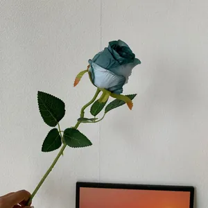 Close-up detail of a single stem teal artificial Bulgarian rose flower for decor