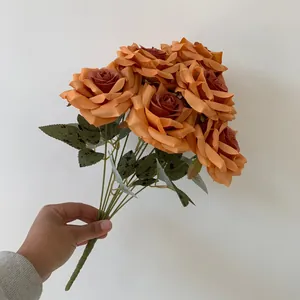 A handheld bouquet featuring nine burnt orange artificial diamond roses for wedding decor.