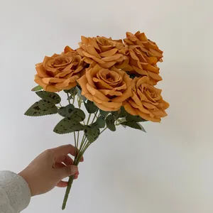 High-quality detail view of artificial burnt orange nine-head rose bouquet held by hand