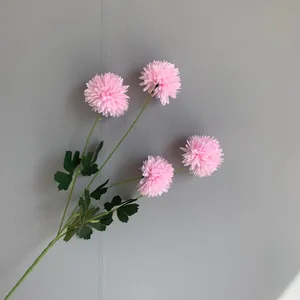 Detail view of 4-head pink artificial pompom chrysanthemum flowers against grey wall