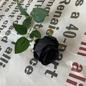 Close-up of a realistic single stem black artificial rose with dark green leaves
