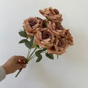 Detailed view showing a vintage dusty rose artificial flower bouquet held by hand