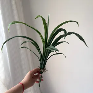 Detail view of artificial green orchid leaves for floral arrangement held by hand