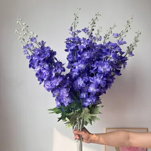 Vista detallada de flores de delphinium artificiales azules flocadas para decorar.