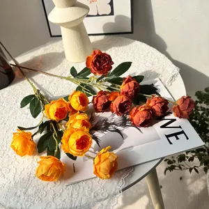 Detailansicht von orangefarbenen künstlichen Pfingstrosen auf einer Tischdecke