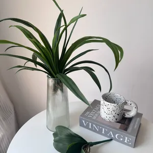 Detailed texture of artificial Cymbidium and Phalaenopsis leaves in a glass vase setup