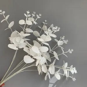 Close-up detail of white artificial eucalyptus bundle held against a minimalist grey wall