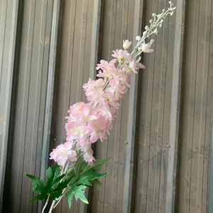 Primer plano detallado de una flor de delphinium rosa artificial con hojas