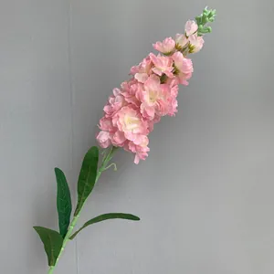 Gedetailleerde close-up van een roze kunstmatige zijden delphinium bloemsteel met blad.