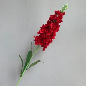 Detailweergave van kunstmatige rode ridderspoor zijden bloem met groene bladeren