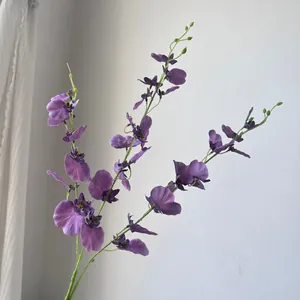 Close-up view of purple artificial dancing lady orchids against a clean white wall.