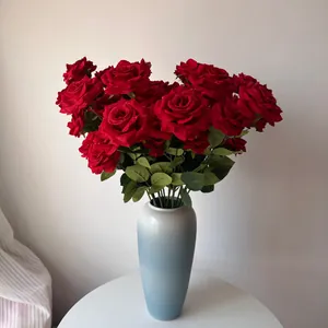 Detailed close-up view of red artificial roses with water droplets in a blue vase