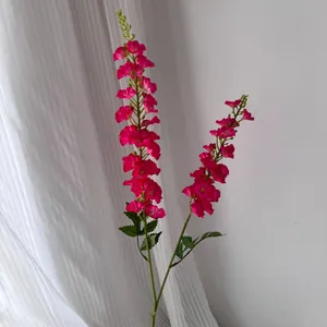 Gros plan de deux tiges de fleurs de dauphinelle artificielles rose fuchsia très éclatantes