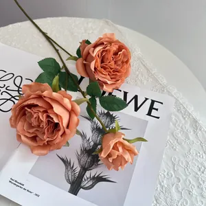 Detailed close-up of burnt orange artificial Austin roses on vintage paper
