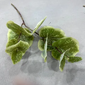 Detailed macro view of artificial green lotus leaf branch with realistic white spots.
