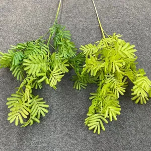 Macro detail showing the realistic texture of green artificial foliage branches for wedding decor.