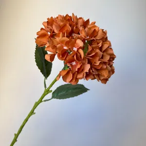 Close-up of a single stem burnt orange artificial hydrangea flower for wedding decor