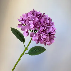 Detailed view of a purple artificial hydrangea stem with realistic green leaves