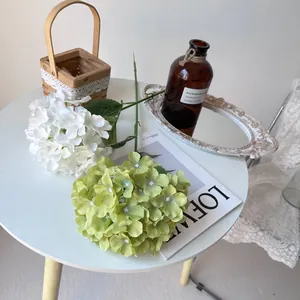 Detailed close-up of white and green artificial hydrangeas arranged on a stylish table