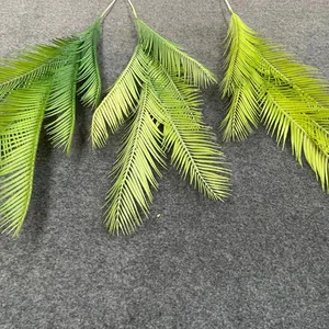 Detail view of artificial cycad palm leaves in three shades of green for wedding decor layout.