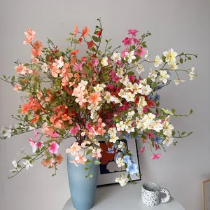 Fleurs de jasmin artificielles colorées disposées dans un vase bleu minimaliste