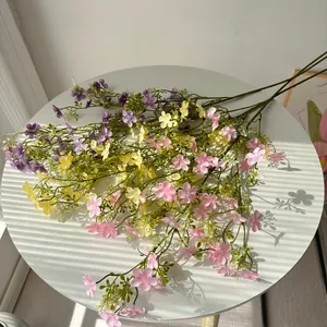 Detailansicht bunter künstlicher Wildblumen auf einem weißen Tisch mit Lichtschatten