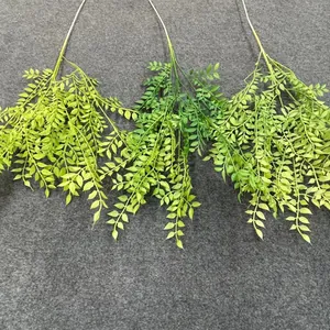 Detail view of three artificial green leaf branches in different shades for decor.