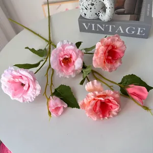 Primer plano de elegantes rosas de lisianthus de seda rosa en una mesa blanca con accesorios.