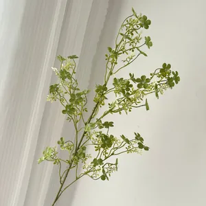 Detaillierte Makroansicht eines künstlichen grünen Zweigs mit kleinen weißen Knospen