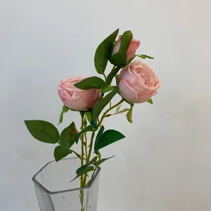 Detailed close-up of three artificial pink silk roses in a glass vase for home decor.