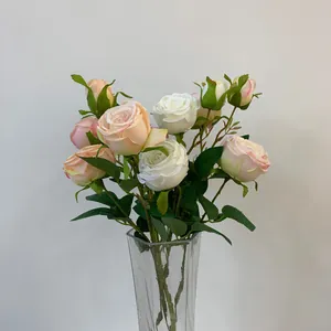 Close-up of artificial white and peach silk roses in a clear glass vase decoration