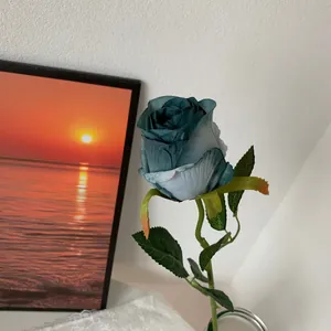 Detailed close-up of a realistic teal artificial Bulgarian rose with fabric petals