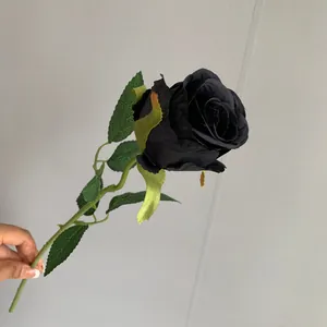 Detailed view of a realistic black artificial rose stem held by hand for home decoration