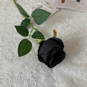 Detailed macro view of a single black artificial Bulgaria rose on white lace tablecloth