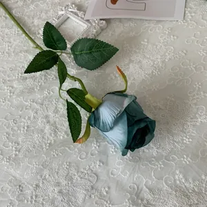 Close-up of a single stem blue artificial Bulgaria rose on white lace background