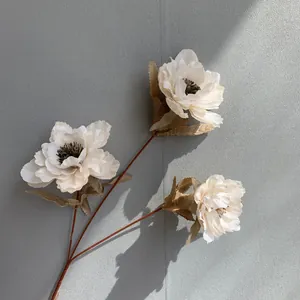Detailed view of 3-head white artificial peony silk flower against grey wall
