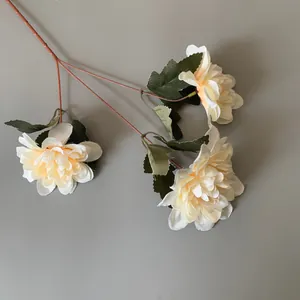 Detaillierte Nahaufnahme eines champagnerfarbenen Kunstblumenzweigs mit drei Blüten.