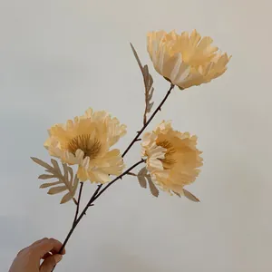 Detailansicht eines champagnerfarbenen Kunstblumenzweigs mit drei großen Blüten.