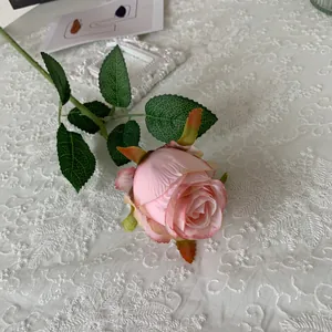 Detailed view of a single elegant artificial pink Bulgarian rose on white lace tablecloth