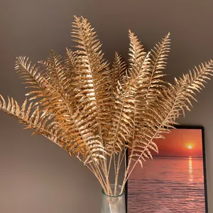 Nahaufnahme von glänzenden goldenen künstlichen Farnblättern für die Wohndekoration