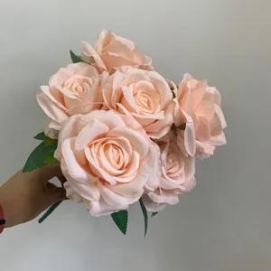 Handgehaltene Detailansicht eines champagnerfarbenen künstlichen Rosenstraußes für Hochzeiten