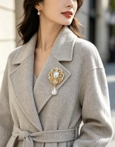 Elegant vintage crown brooch with pear-shaped rhinestones on a grey wool coat detail.