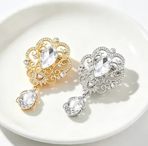 Close-up of vintage crown brooches with teardrop crystals in gold and silver tones.