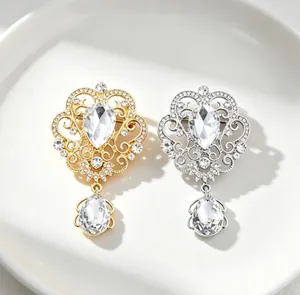 Detailed view of elegant gold and silver crown brooches featuring teardrop crystal pendants