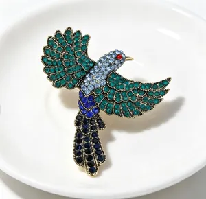Detail der Vintage-Elster-Brosche mit lebendigen grünen und blauen Strasssteinen